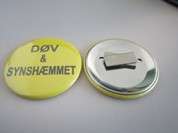 Gul badge med magnet. Tekst: Døv og Synshæmmet